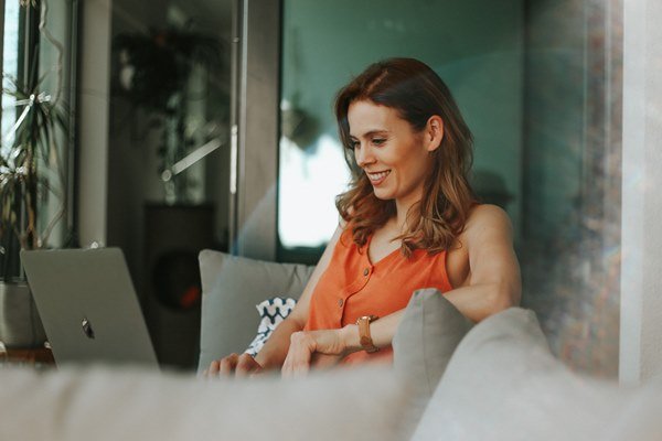 Woman in orange shirt working on a laptop