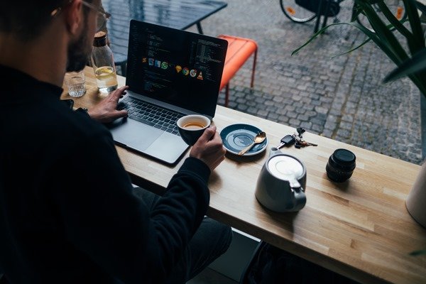 Man working on a laptop and drinking coffee