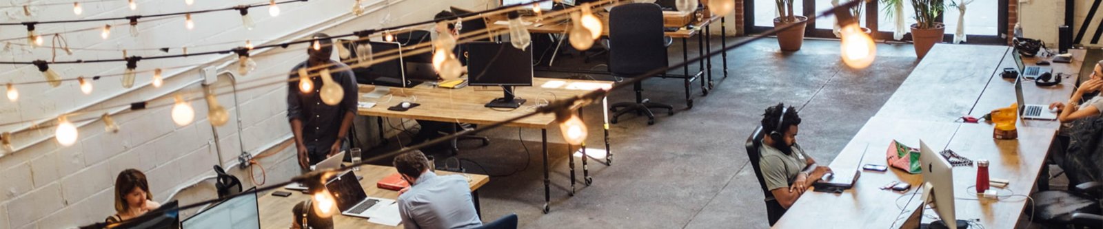 People working in a coworking space with fairy lights stretched above them