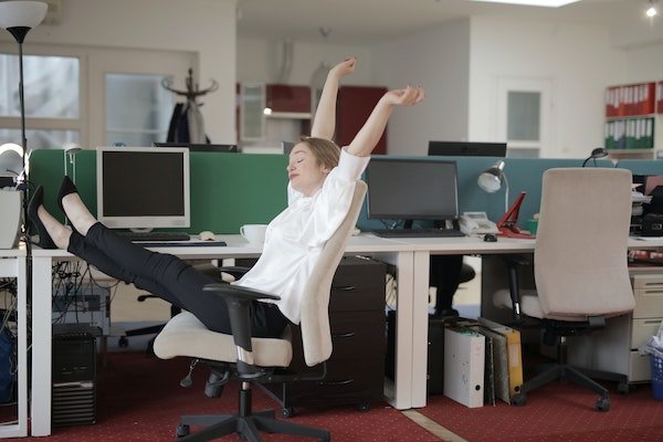 Woman stretching her legs in her chair at her desk at the office