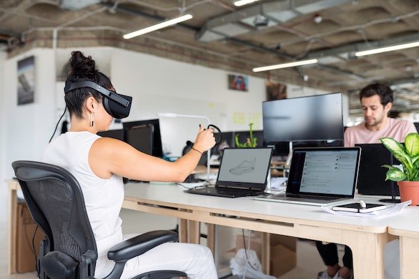 Woman using 2 laptops and a vr set at work